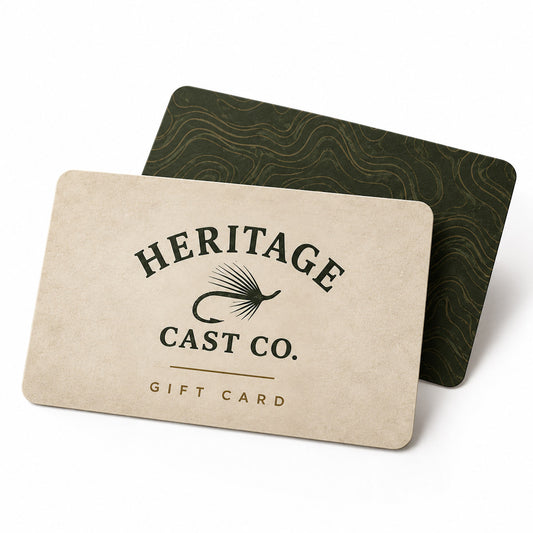 A Heritage Cast Co. gift card in a light beige textured paper style with black text and logo, shown in front of a dark green patterned card on a clean white background.