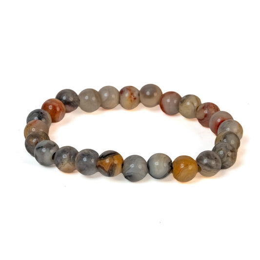 A beaded stretch bracelet made of round, polished stone beads in earthy gray, brown, and black tones, arranged in a circle on a white background.