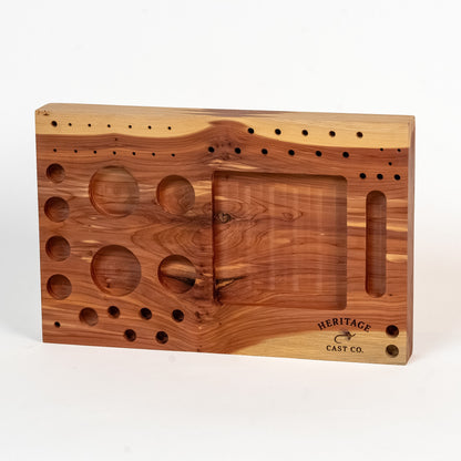 A rectangular wooden casting mold with a warm honey and medium brown wood grain pattern, featuring circular and oval cavities, a central rectangular opening, and the 'HERITAGE CAST CO.' logo in the bottom right corner, set against a plain white background.