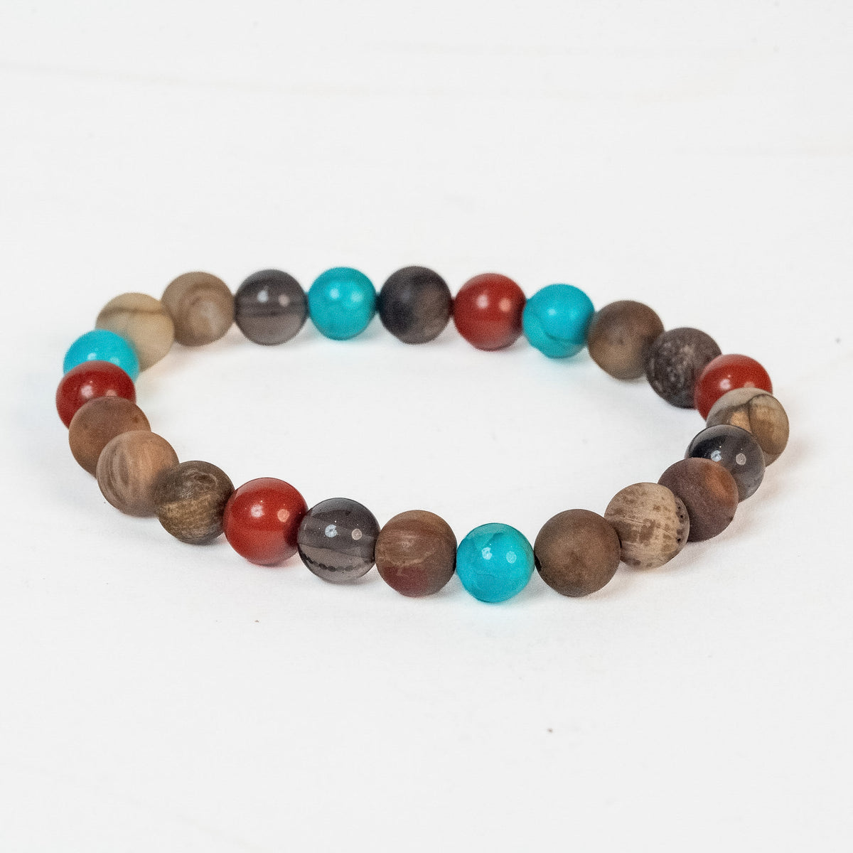 A beaded stretch bracelet made of round wooden beads in various natural brown tones, with a few turquoise blue and red beads, displayed on a clean white background.