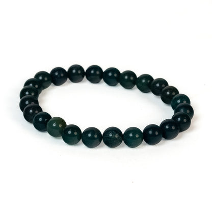 A beaded stretch bracelet made of dark green faceted round beads, displayed on a clean white background.