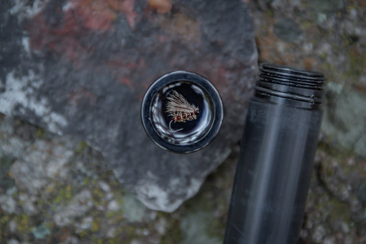 Fly fishing fly in lid of cigar tube cap.