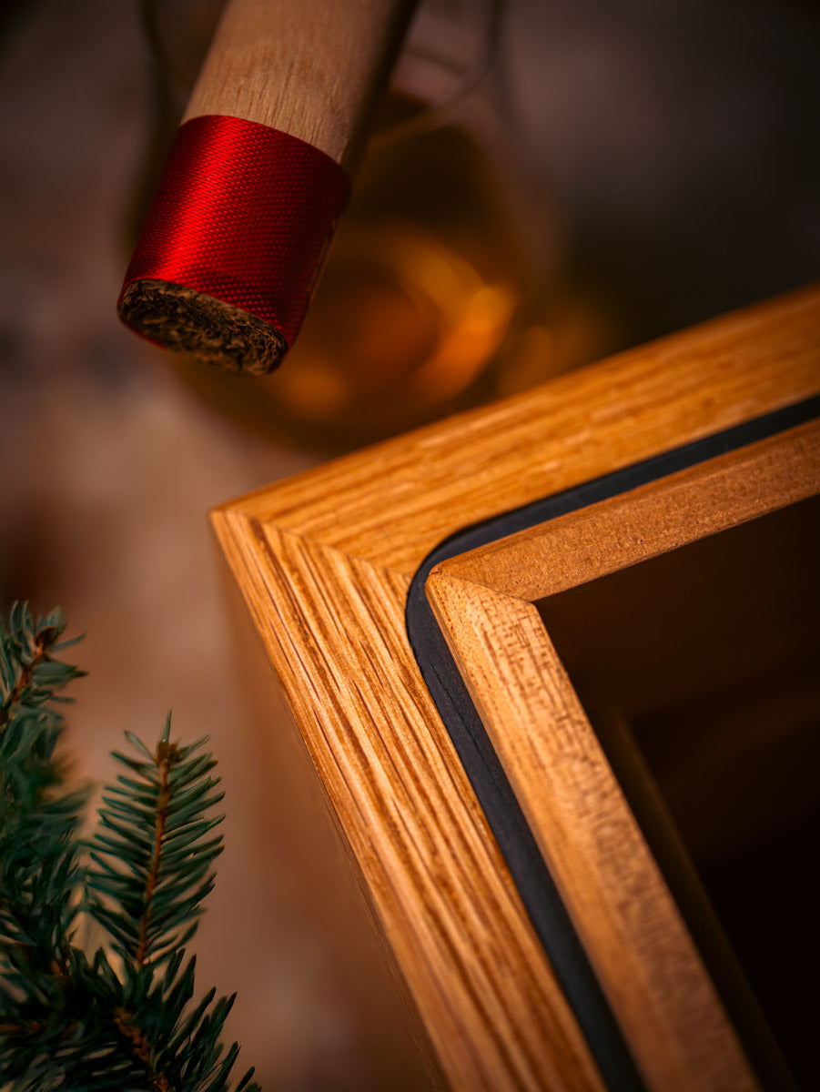 Wooden humidor with a red ribbon around a cigar and a blurred background